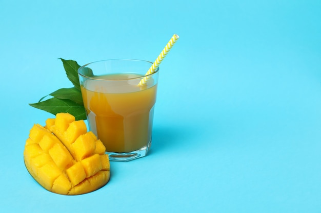 Fruits et jus de mangue mûrs sur fond bleu