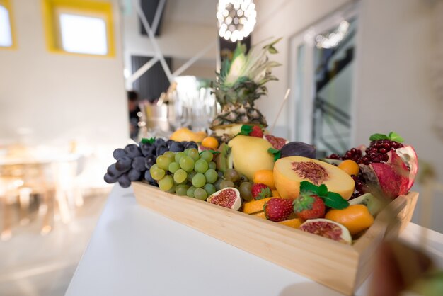 Photo fruits juteux dans une boîte en bois ananas raisins mangue figue pêche fraise fruit du dragon