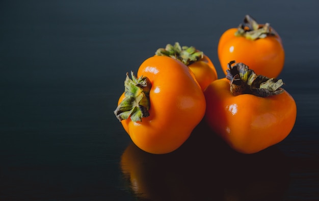 Fruits de kaki frais délicieux sur fond noir.