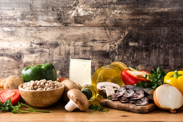 Fruits, légumes, céréales, noix, huile d'olive et poisson sur table en bois