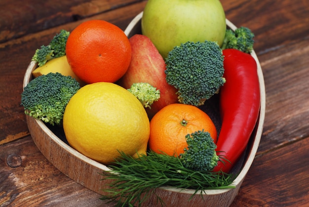 Fruits et légumes dans une boîte en bois en forme de coeur. Brocoli, pommes, poivrons, tangeriners.