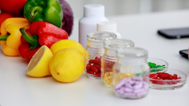 Photo fruits et légumes, pilules rouges, vertes, jaunes dans plusieurs bouteilles, table de nutritionniste de téléphone portable. concept pour la photographie de vue de dessus de table de nutrition.