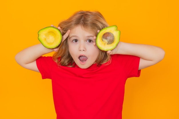 Fruits et légumes sains pour les enfants Kid tenir avocat rouge en studio Studio portrait d'enfant mignon avec avocat isolé sur fond jaune