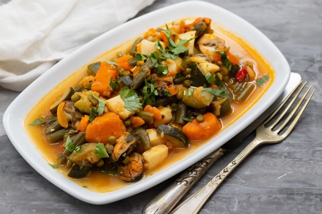 Fruits de mer aux légumes et herbes sur plat blanc