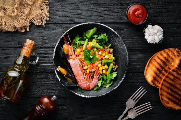 Fruits de mer aux légumes Légumes bouillis aux crevettes et moules Dans une assiette noire Vue de dessus Espace de copie gratuit