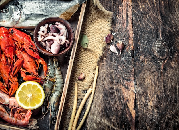 Fruits de mer dans un vieux plateau. Sur un fond en bois.