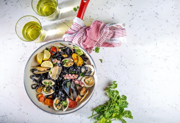 Fruits de mer fettuccine fehttuchini noir pâtes noires aux calmars poulpe palourdes moules sur plaque de pierre rendez-vous