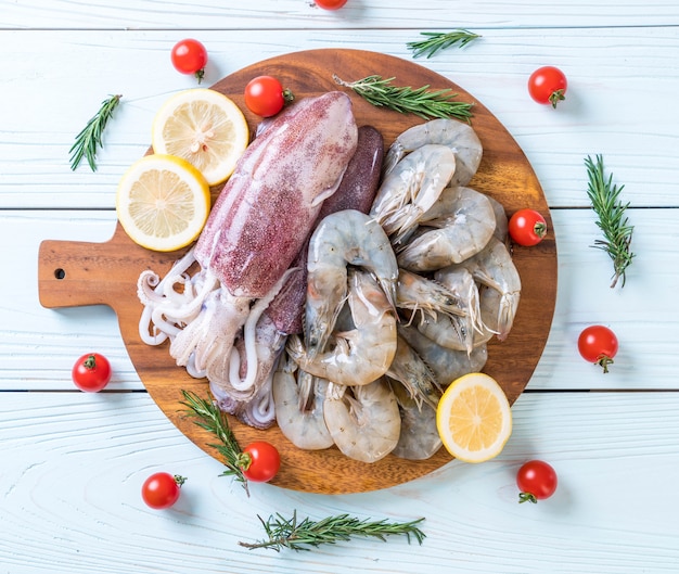 Fruits de mer frais crus (crevettes, calamars) sur une planche de bois