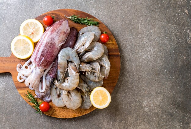 Fruits de mer frais crus (crevettes, calamars) sur une planche de bois