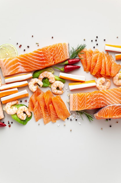 Fruits de mer frais sur table avec épices, légumes et huile d'olive: saumon frais et fumé, crevettes et bâtonnets de crabe pour un supermarché ou un restaurant de sushi de poisson.