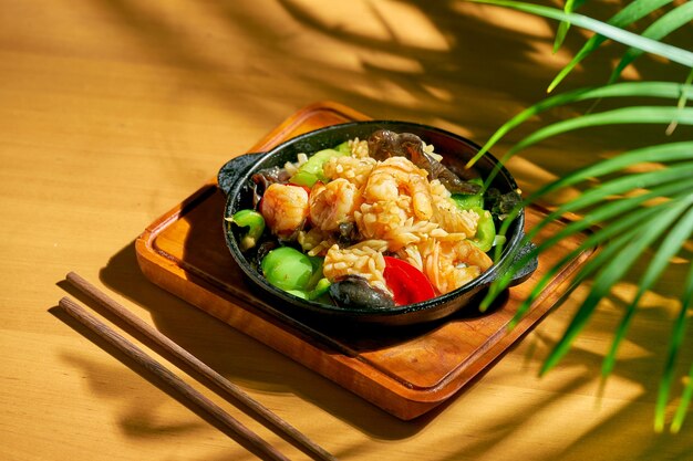 Fruits de mer frits (crevettes, moules, calamars) dans une sauce aigre-douce, avec du poivre de Sichuan dans une poêle. Fond de bois. cuisine chinoise