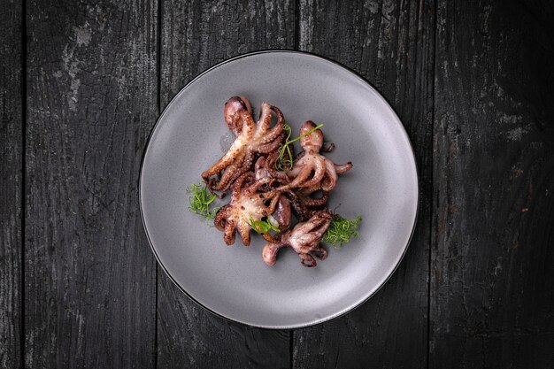 fruits de mer grillés dans une assiette ronde grise sur une table en bois foncé