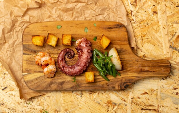 Fruits De Mer Grillés Grecs Traditionnels Sur Une Planche à Découper En Bois Servi Avec Des Crevettes Et Des Légumes De Style Rustique. Délicieux Tentacule De Poulpe Barbecue Avec Vue De Dessus De Légumes Frais