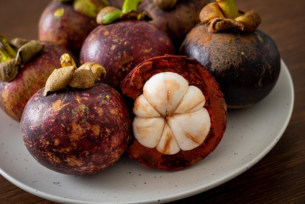 Fruits mûrs frais de mangoustan sur plaque blanche