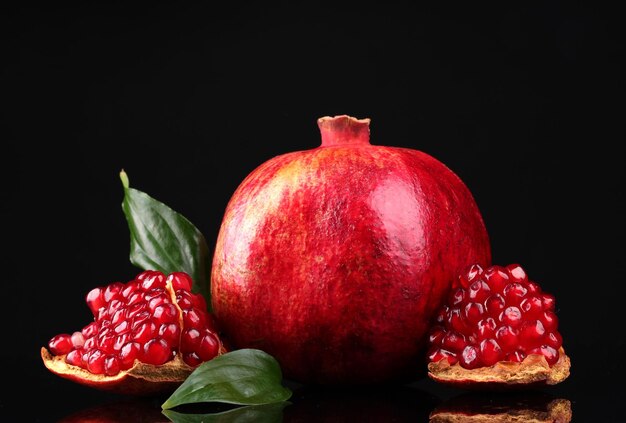 Fruits mûrs de grenade avec des feuilles sur le fond noir