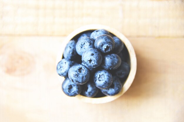 Fruits de myrtilles fraîches dans un bol sur une table en bois