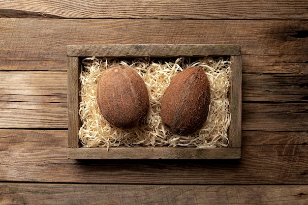 Fruits de noix de coco tropical frais dans une boîte de livraison en bois sur une table en bois. Concept d'alimentation saine, vue de dessus.