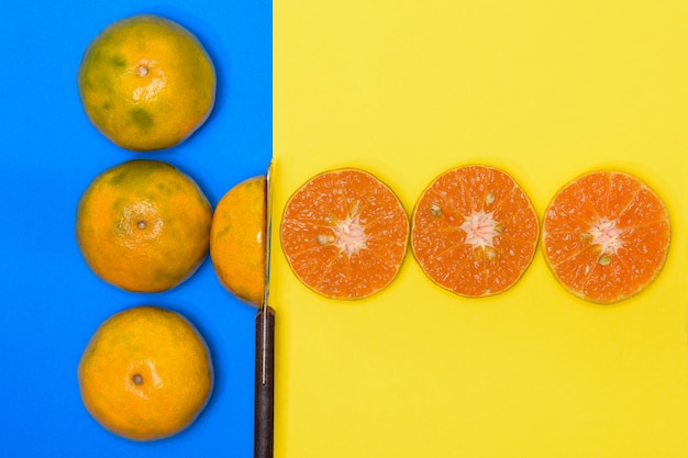 Fruits orange et orange à moitié coupés sur des fonds bleus et jaunes.