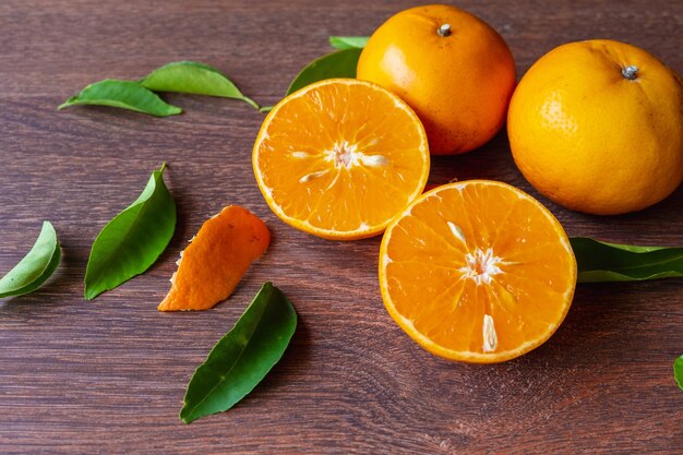 Fruits oranges frais et fruits orange coupés en deux sur une table en bois