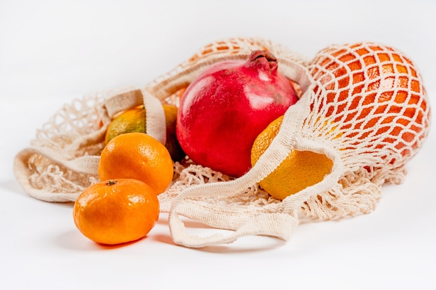 Les fruits de pamplemousse et de grenade mandarines se trouvent dans un éco-sac en coton sur fond blanc