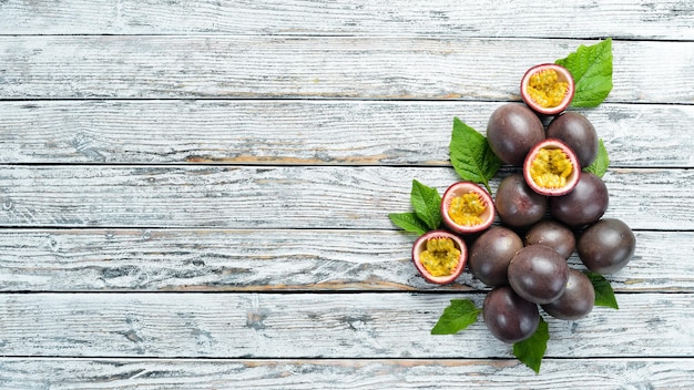 Fruits de la passion avec une feuille sur un fond en bois blanc. Fruits tropicaux. Vue de dessus. Espace libre pour le texte.