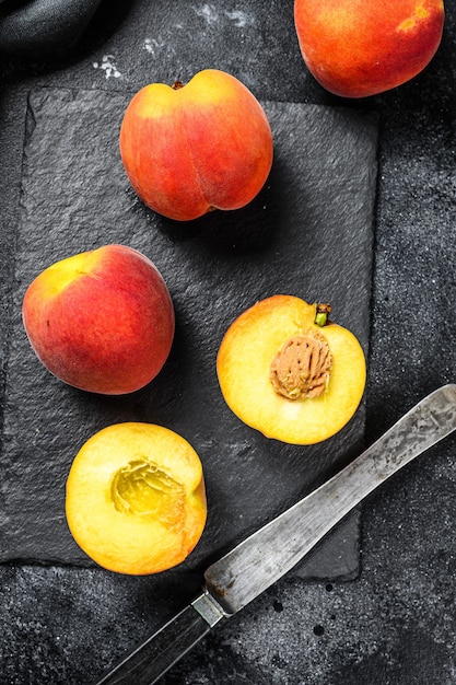 Fruits de pêches biologiques sur une planche de pierre noire.