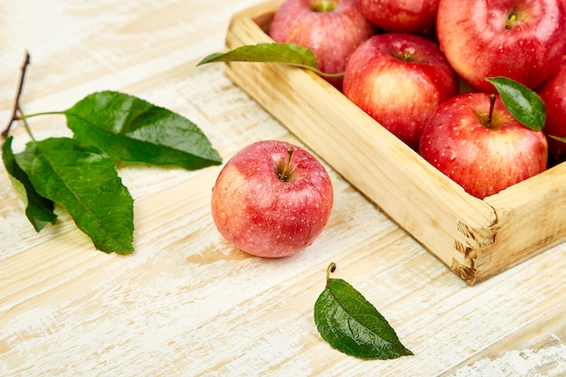 Fruits de pommes mûres rouges fraîches dans la boîte en bois.