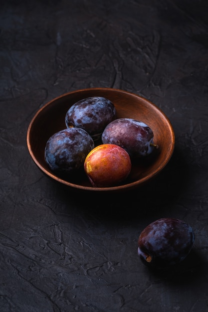 Fruits de prune douce fraîche dans un bol en bois brun