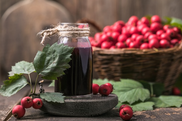 Fruits rouges d'aubépine fraîche dans le panier debout sur une table en bois