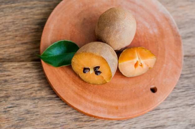 Fruits de sapodilla frais sur fond de bois ancien