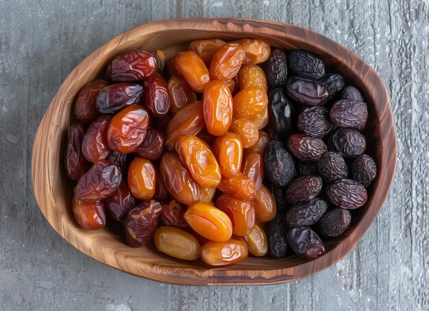 fruits secs assis avec des dattes sur un plateau en bois et une boîte sur une texture grise