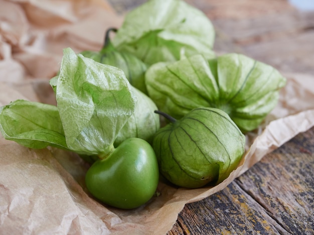 Fruits de tomates vertes fraîches sur papier sur table en bois rustique ingrédient salsa verde.