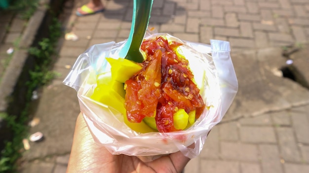 Photo des fruits tranchés avec de la sauce au piment sur une tasse de nourriture asiatique manisan rujak pedas