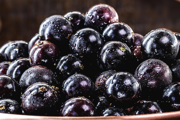 Fruits tropicaux brésiliens et sud-américains de Jabuticaba dans un pot en cuivre sur une table rustique