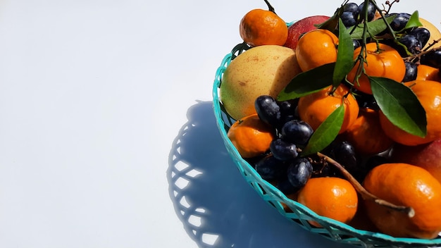 Fruits tropicaux dans un panier vert à droite sur fond blanc 01