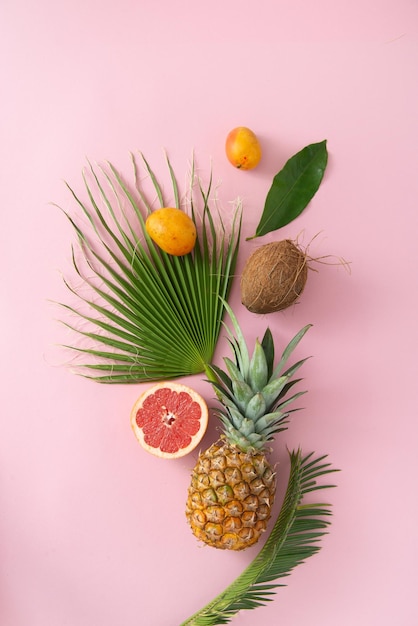 fruits tropicaux et feuilles sur fond rose vue de dessus