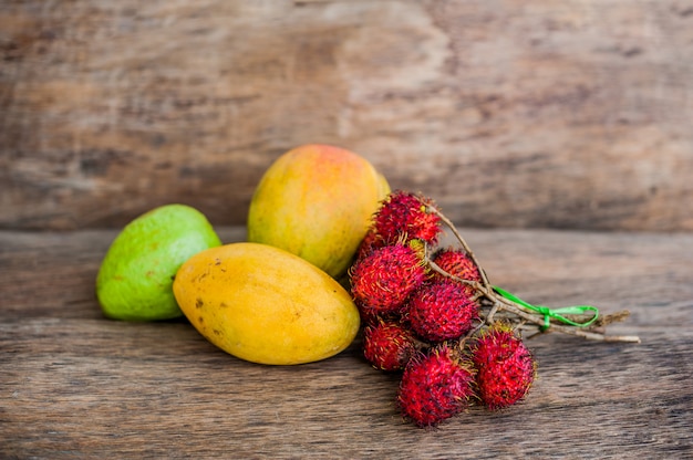 Fruits tropicaux sur le vieux fond en bois. Ramboutan, banane, mangue, goyave.