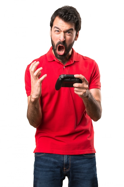 Frustré beau jeune homme jouant des jeux vidéo sur fond blanc isolé