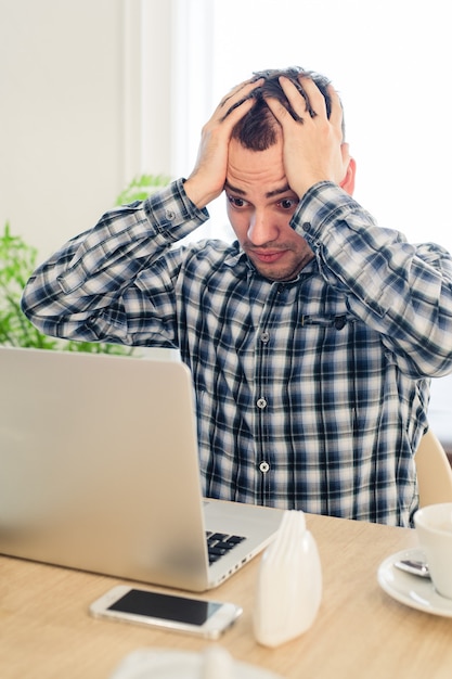 Photo frustré jeune homme travaillant sur un ordinateur portable