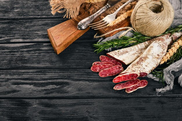 Fuet Salami et Saucisse espagnole traditionnelle au romarin Sur fond de bois noir Vue de dessus