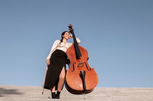 Full shot femme dans les escaliers avec contrebasse