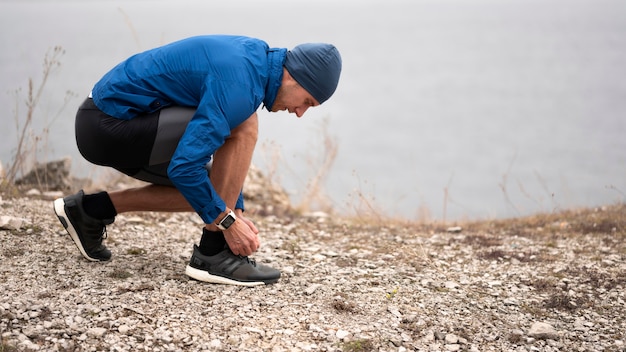 Photo full shot homme attachant ses lacets sur le sentier