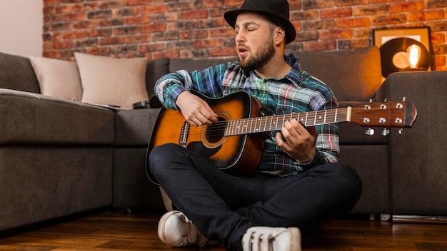 Full shot homme jouant de la guitare sur marbre