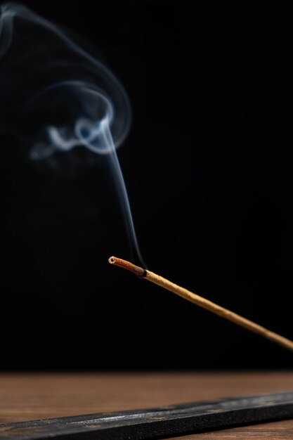 Photo fume d'un bâton d'arôme brûlant sur un fond noir bâton d'encens aromathérapie et méditation