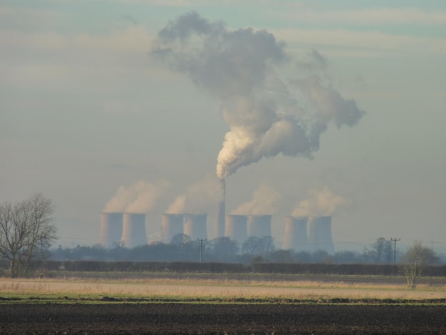 Fume émise par la cheminée sur le champ contre le ciel