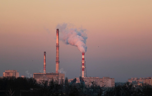 Fume émise par l'industrie contre le ciel au coucher du soleil