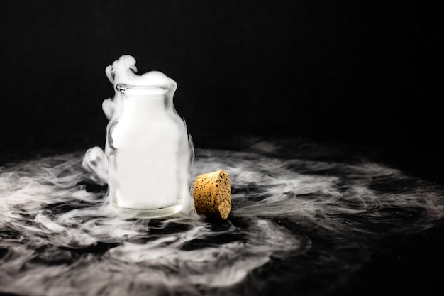 Fumée blanche à l&#39;intérieur de la bouteille en verre sur fond noir