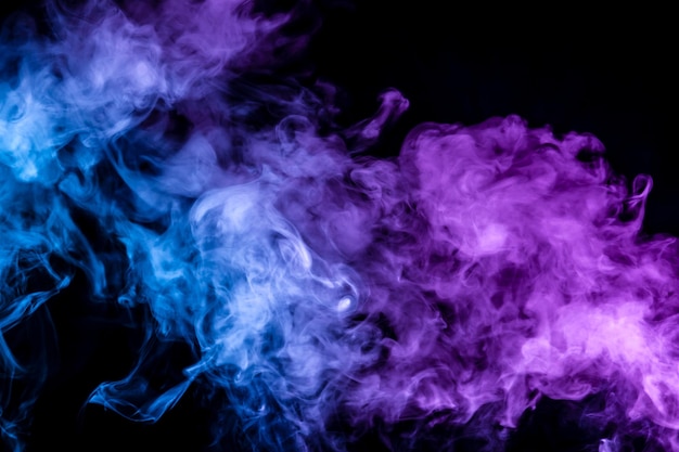 La fumée épaisse translucide éclairée par la lumière sur un fond sombre divisé en trois couleurs bleu vert et violet brûle en s'évaporant d'une vapeur de vape
