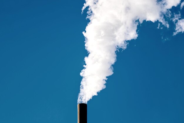 Fumée industrielle du tuyau sur fond de ciel bleu