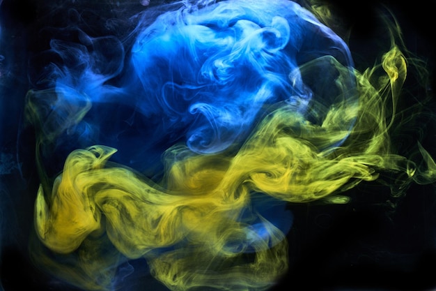 Fumée jaune bleue sur fond d'encre noire, brouillard coloré, mer océanique tourbillonnante abstraite, pigment de peinture acrylique sous l'eau